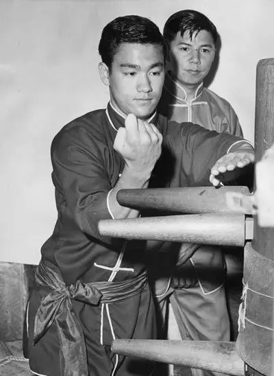 Bruce Lee pratique le kung-fu avec un mannequin en bois